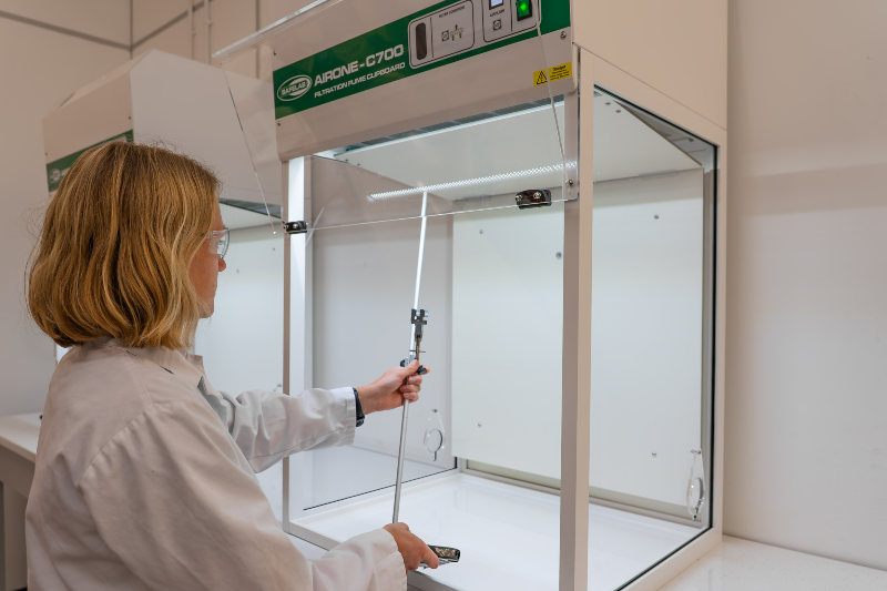 Female lab technician lifting equipment into spacious Airone C700 fume cupboard