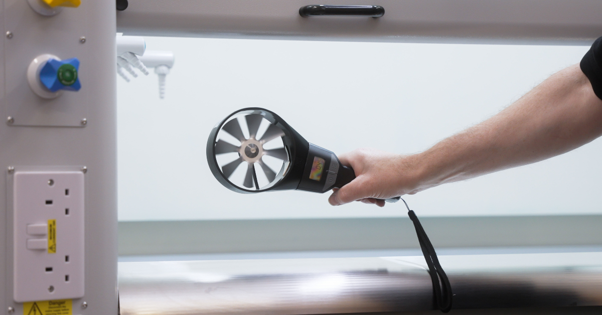 Measuring airflow at a fume cupboard using an anemometer during commissioning in a UK laboratory